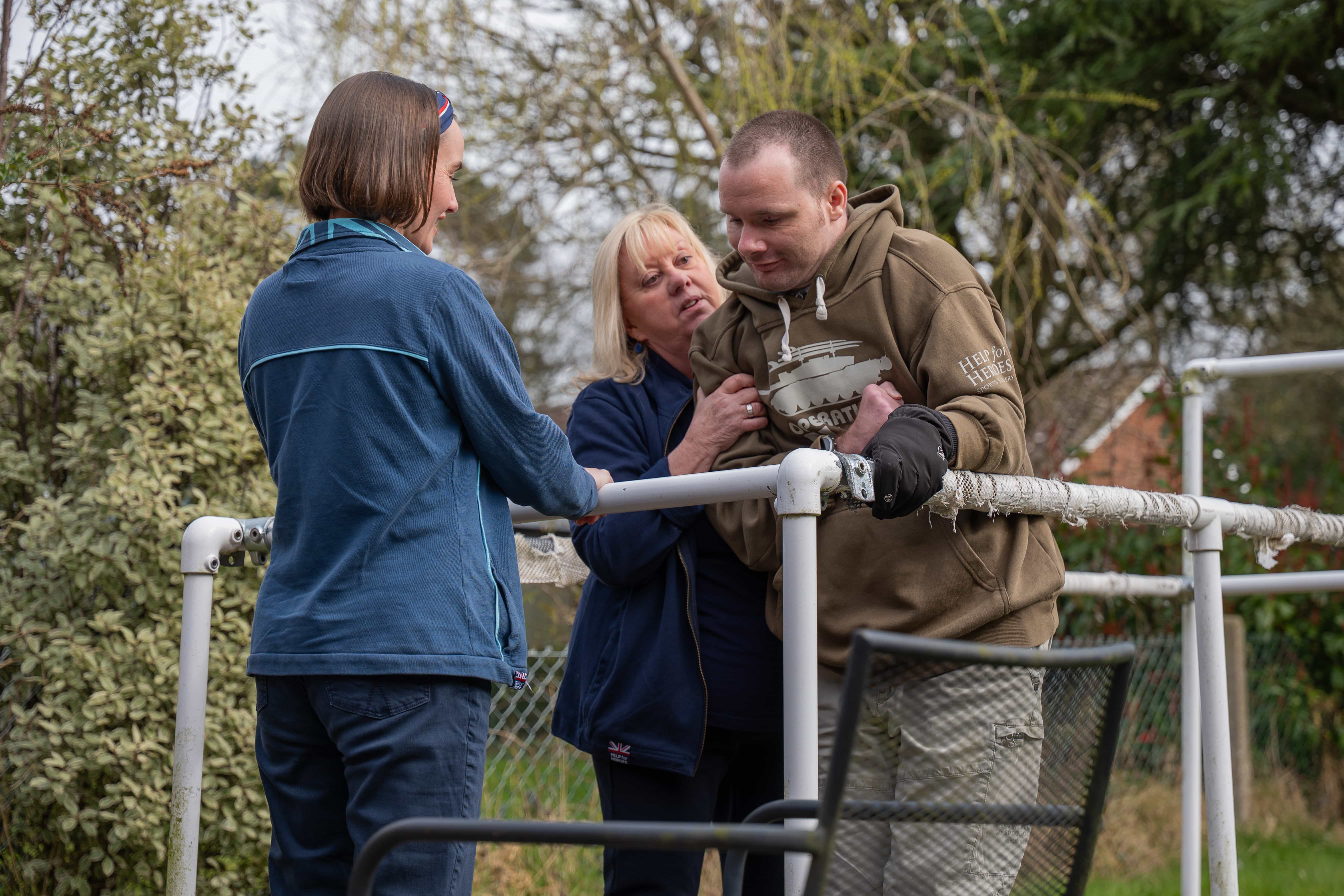 Smiling woman standing beside man in wheelchair